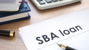 A photo of an office table with a paper written SBA loan with calculator, notebook and pen