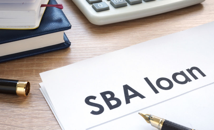 A photo of an office table with a paper written SBA loan with calculator, notebook and pen