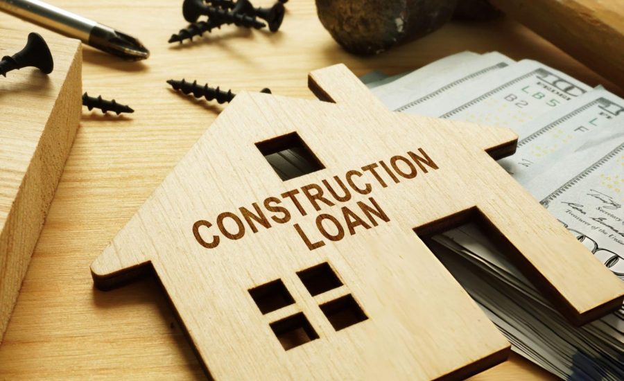 Construction loan lenders near me—wooden house cutout with tools and cash on work surface.