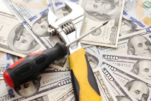 Fix and flip loans near me—wrench and screwdriver placed on U.S. $100 bills symbolizing repair costs and profits.