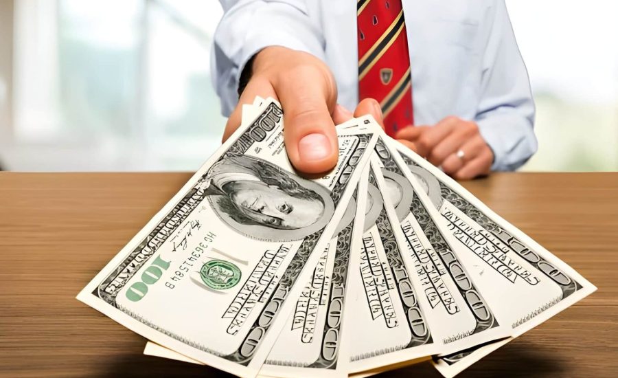 Hard money lenders near me—person in formal attire offering $100 bills at table.