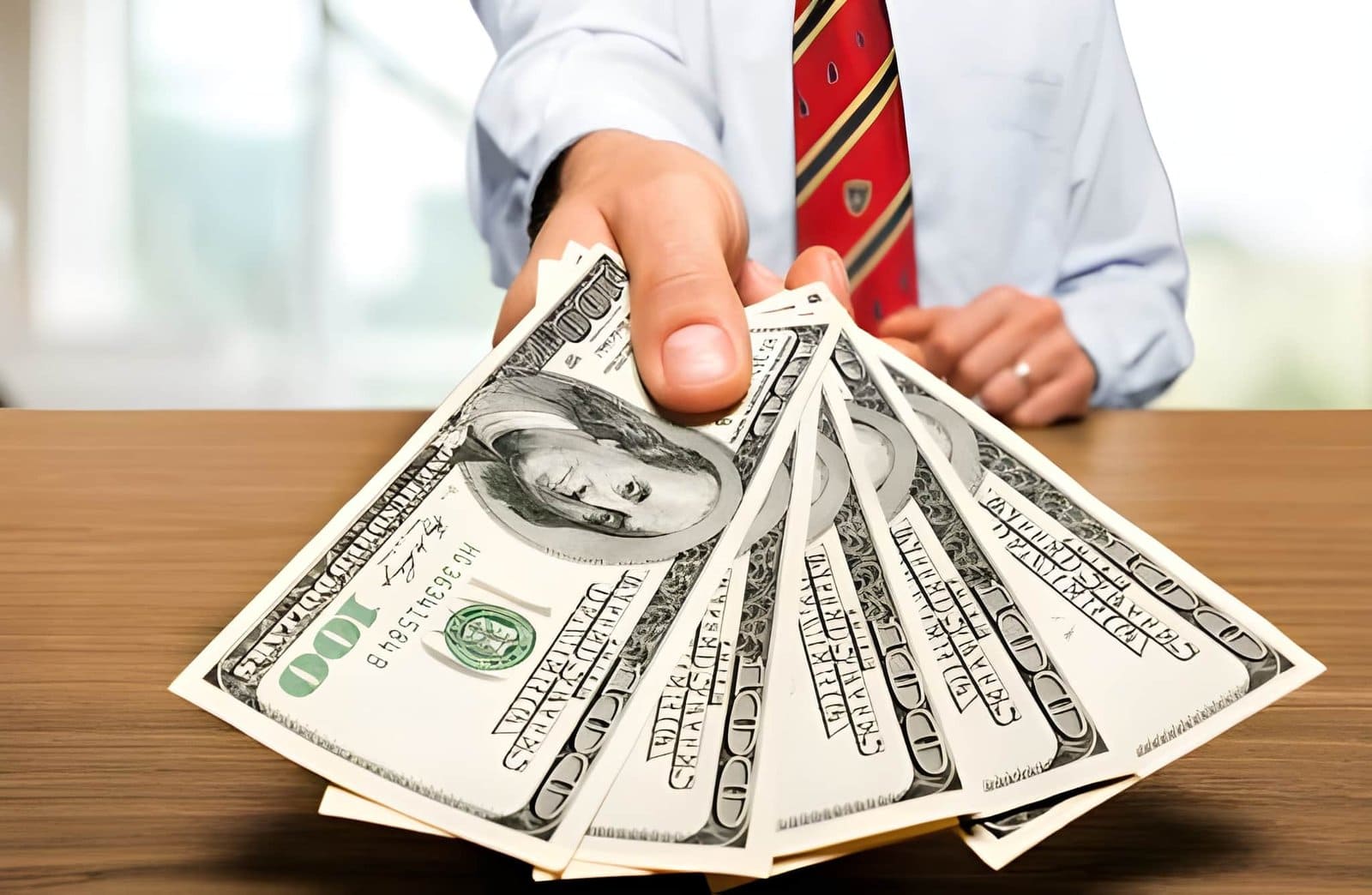 Hard money lenders near me—person in formal attire offering $100 bills at table.