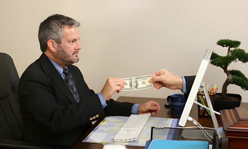 Hard money lenders near me—businessman receiving cash through computer screen in office.